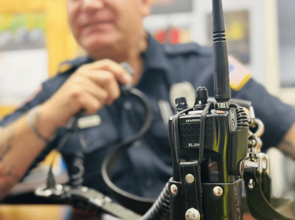 Firefighter speaking on a radio system as part of uniform with radio unit in foreground